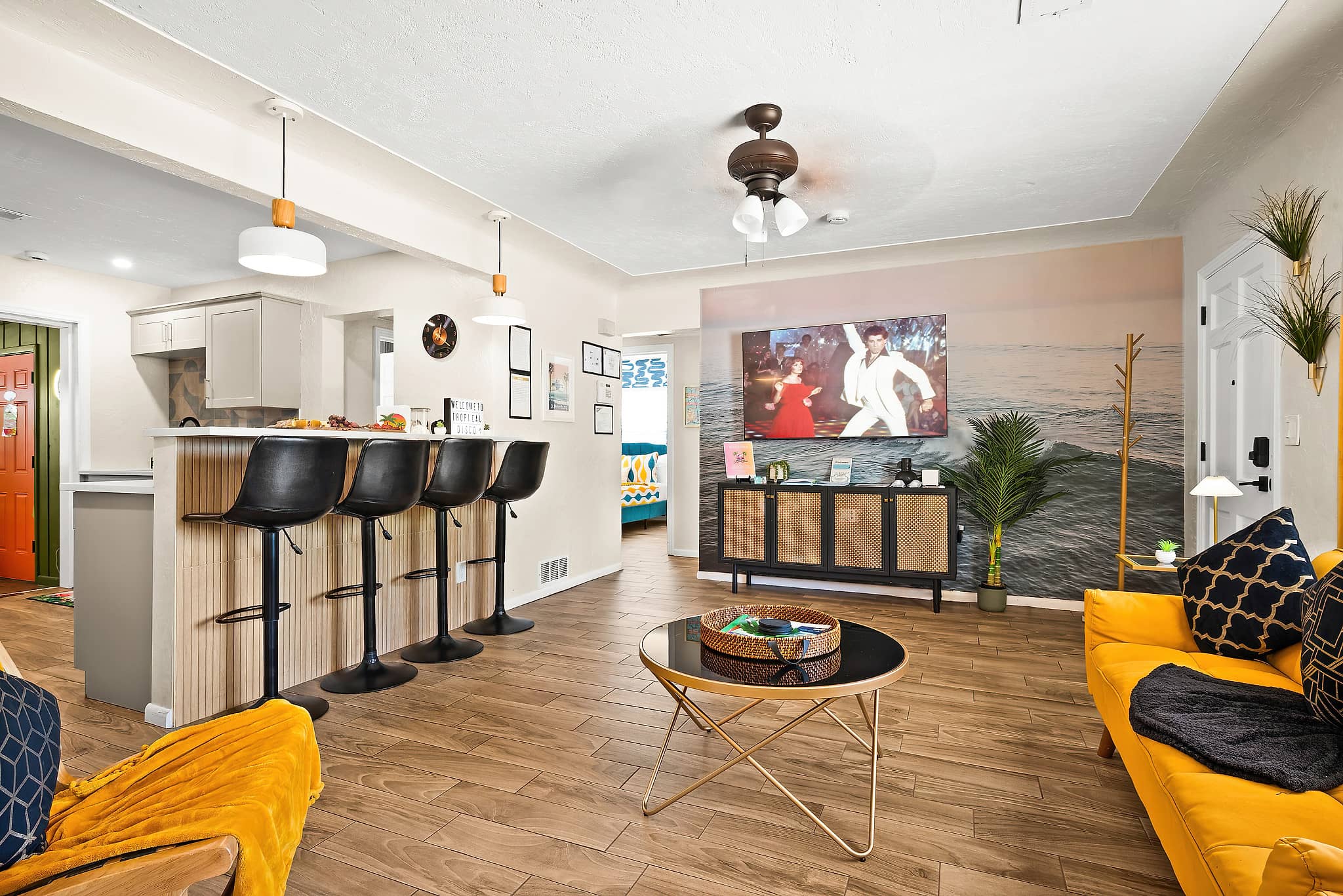 Open plan living room and kitchen with breakfast bar, smart TV and ocean mural at Tropical Disco 4-bedroom vacation rental in St. Petersburg FL