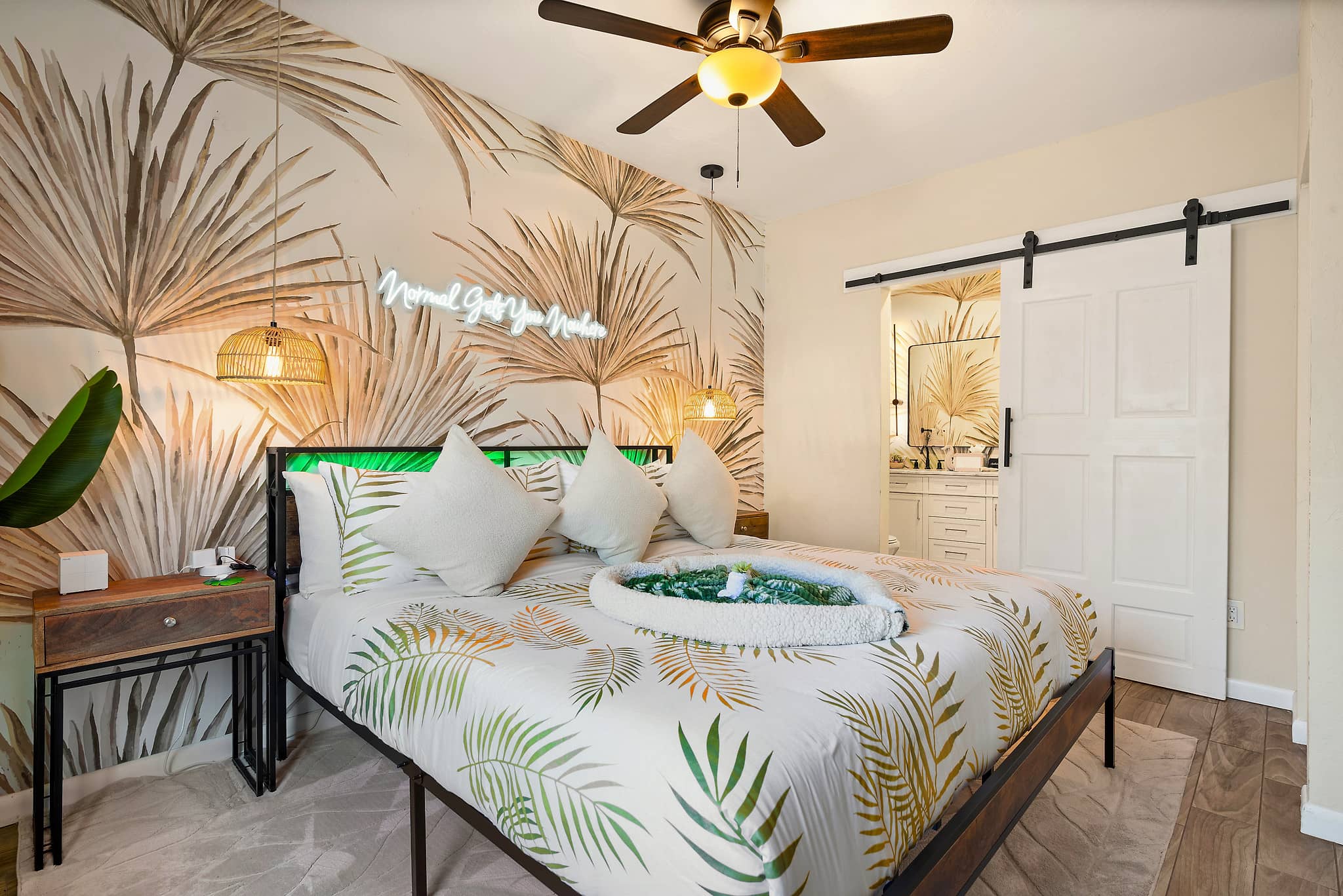 Primary king bedroom with tropical palm mural, neon sign and barn door ensuite at Tropical Disco vacation rental St. Petersburg Florida